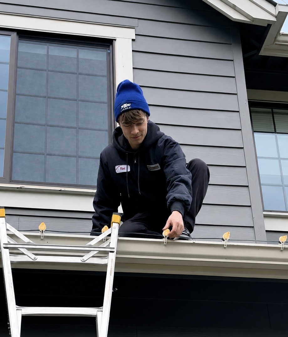 Halen Homes installer clipping bulbs onto a second-story gable