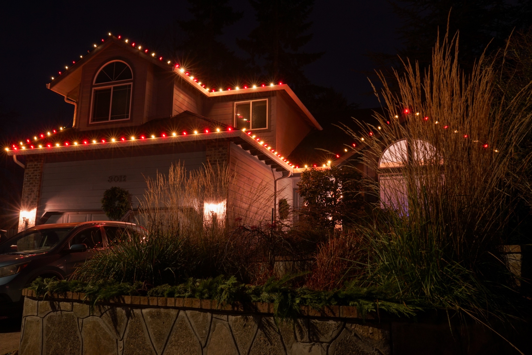 Oregon home with red and warm-white C9 Christmas lights along peaks and gables at night